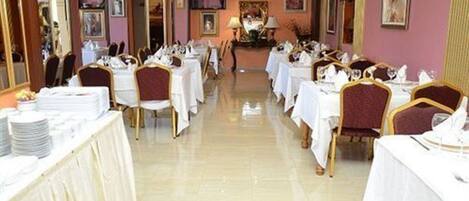 Un comedor formal con mesas dispuestas para el servicio, piso pulido y una pieza decorativa central.