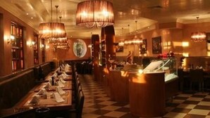A restaurant with a checkered floor, multiple dining tables, and hanging chandeliers.