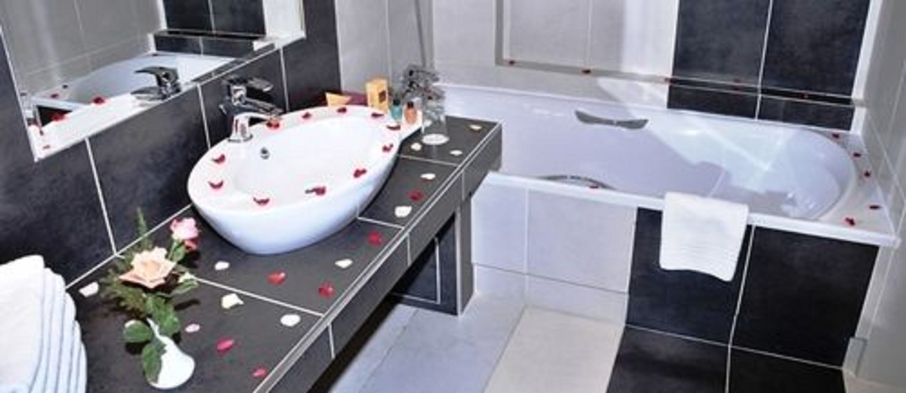 Une salle de bain moderne avec un grand lavabo blanc, une baignoire et un miroir au-dessus du lavabo.