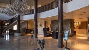 A spacious lobby with a high ceiling, a grand staircase, and a reception desk.