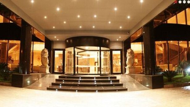 A hotel entrance with a grand staircase, large glass doors, and a well-lit interior.