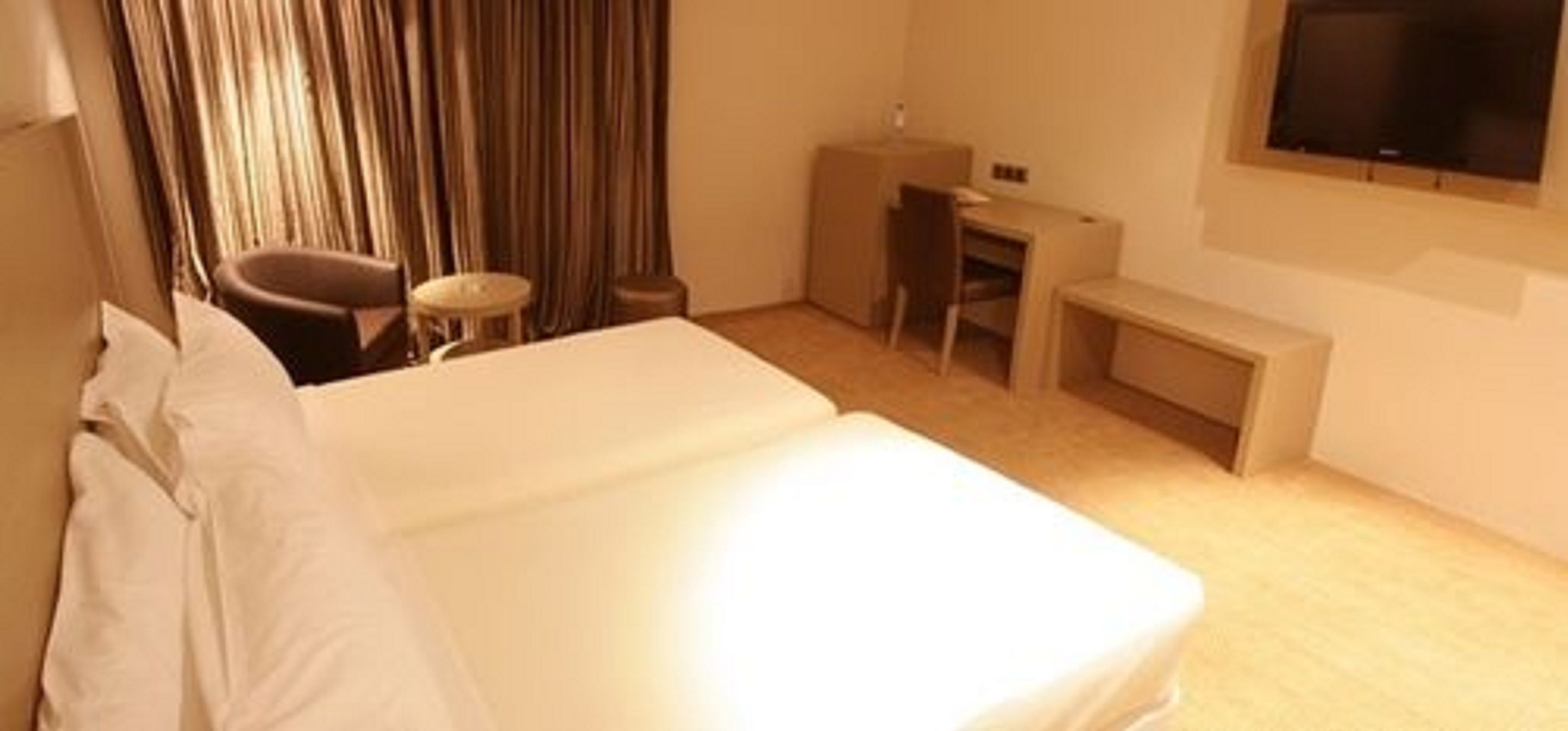 Habitación de hotel con cama, escritorio, silla, mesita y televisión.