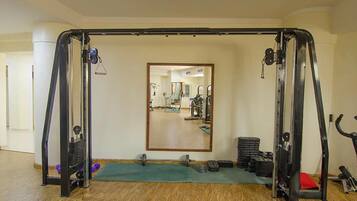 Un gimnasio con barra de dominadas, estantes para pesas y un espejo.