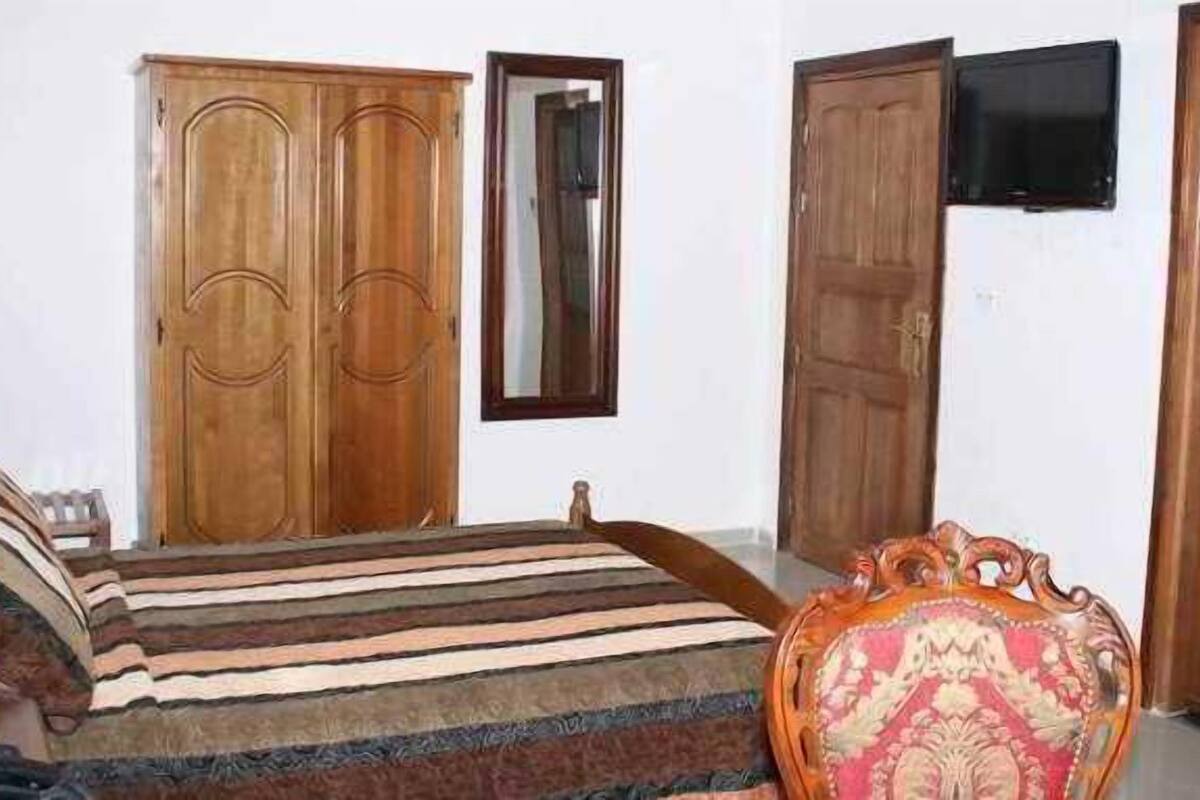 Een slaapkamer met een bed, een kledingkast, een televisie en een stoel.