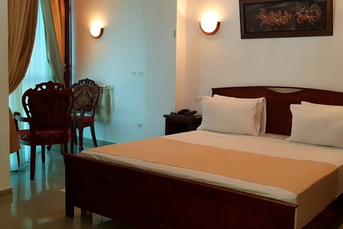 Hotelkamer met een groot bed, twee nachtkastjes, een stoel en een wandlamp.