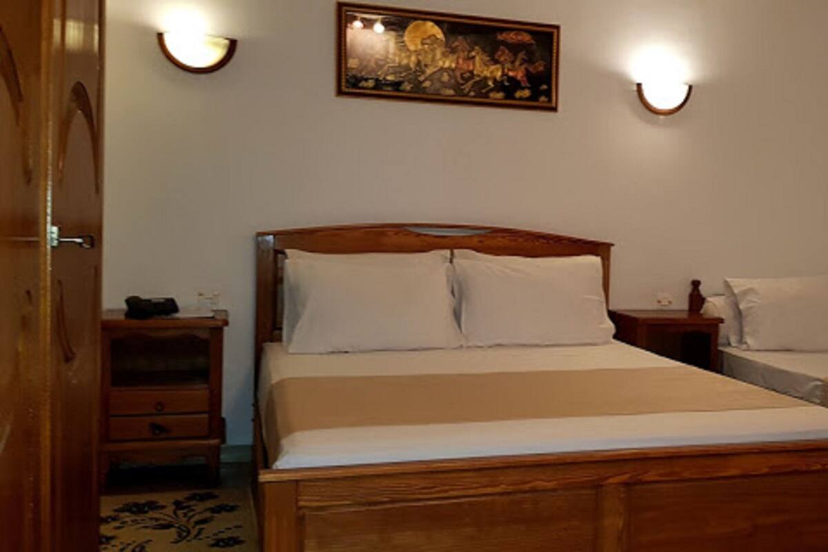 Een slaapkamer met een groot bed, twee nachtkastjes en een schilderij aan de muur.