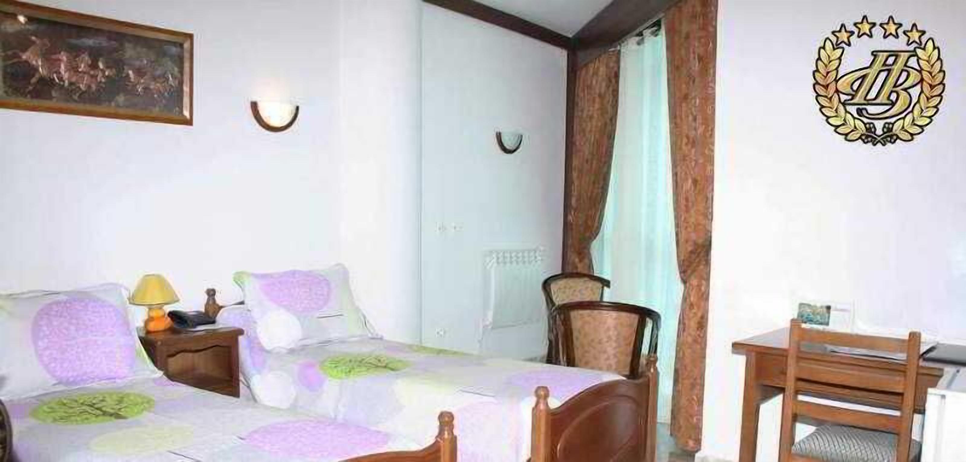 Een slaapkamer met een bed, nachtkastje, lamp, stoel en een bureau met een stoel.