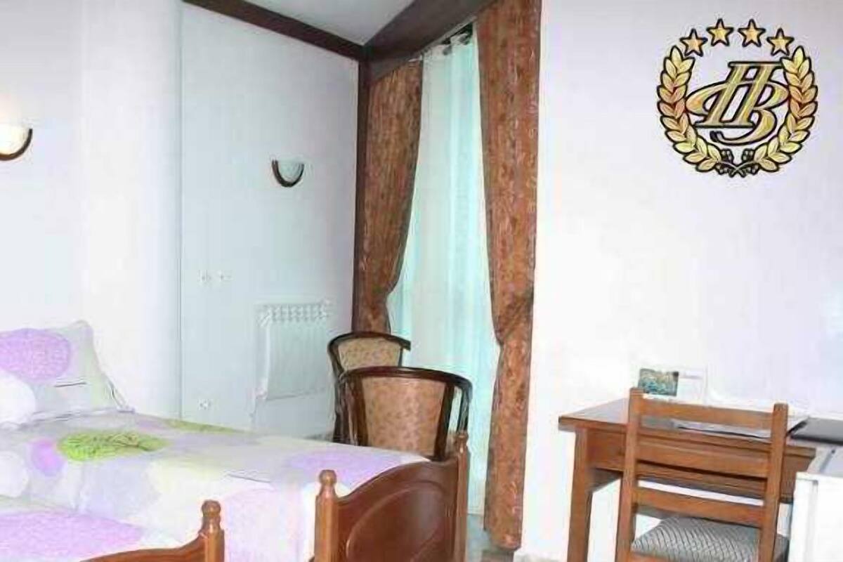 Een slaapkamer met een bed, nachtkastje, lamp, stoel en een bureau met een stoel.