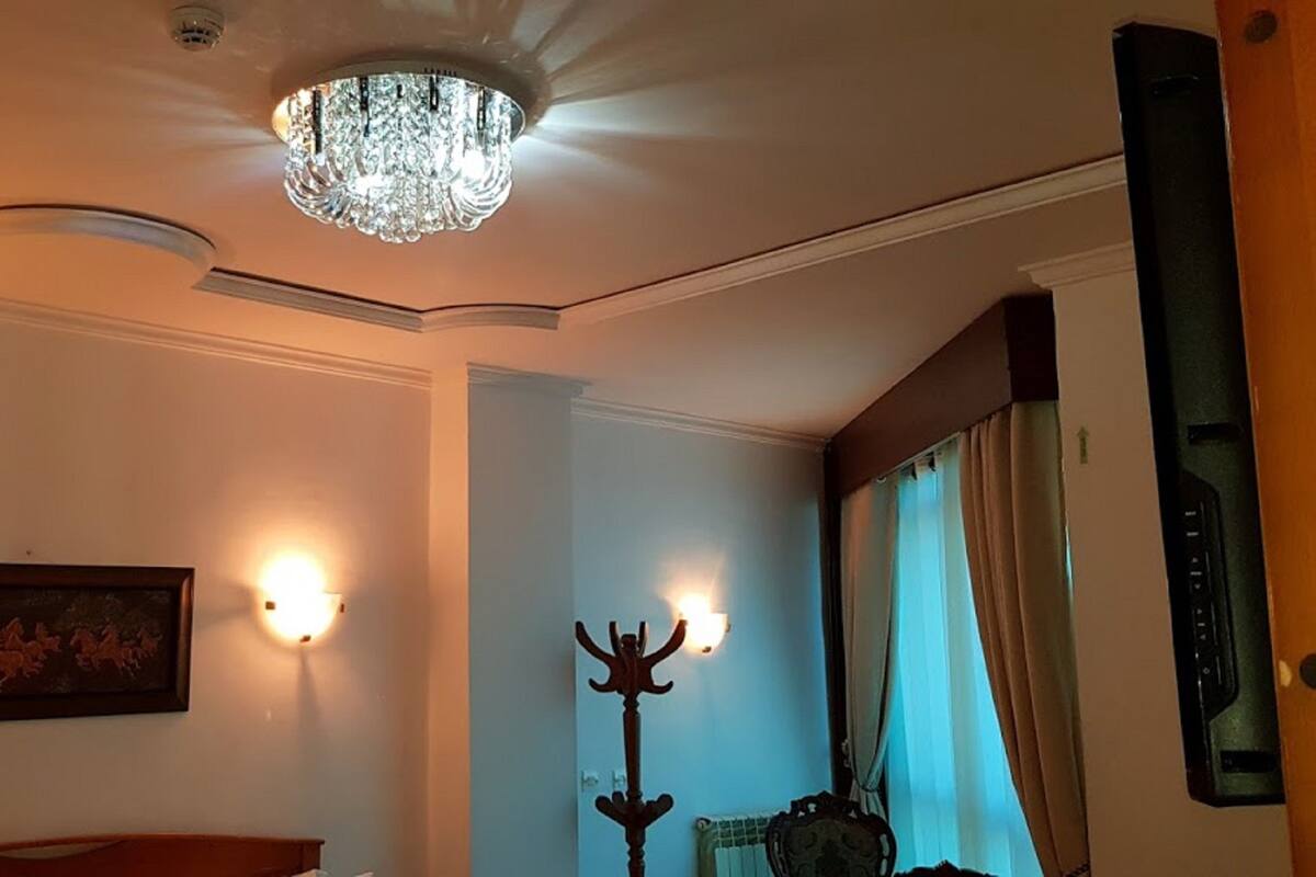 Een kamer met een kroonluchter, wandlampen, een kapstok en een lijstwerk met een afbeelding.