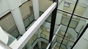 Un intérieur à plusieurs niveaux, doté de rampes en verre et de murs blancs.