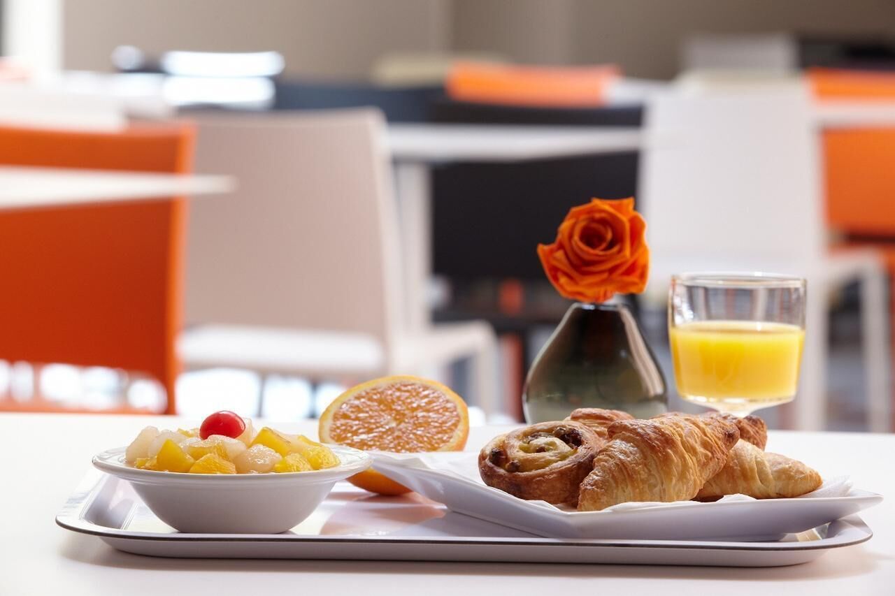 Een ontbijfwagen met fruit, een croissant, een roos en een glas sinaasappelsap.