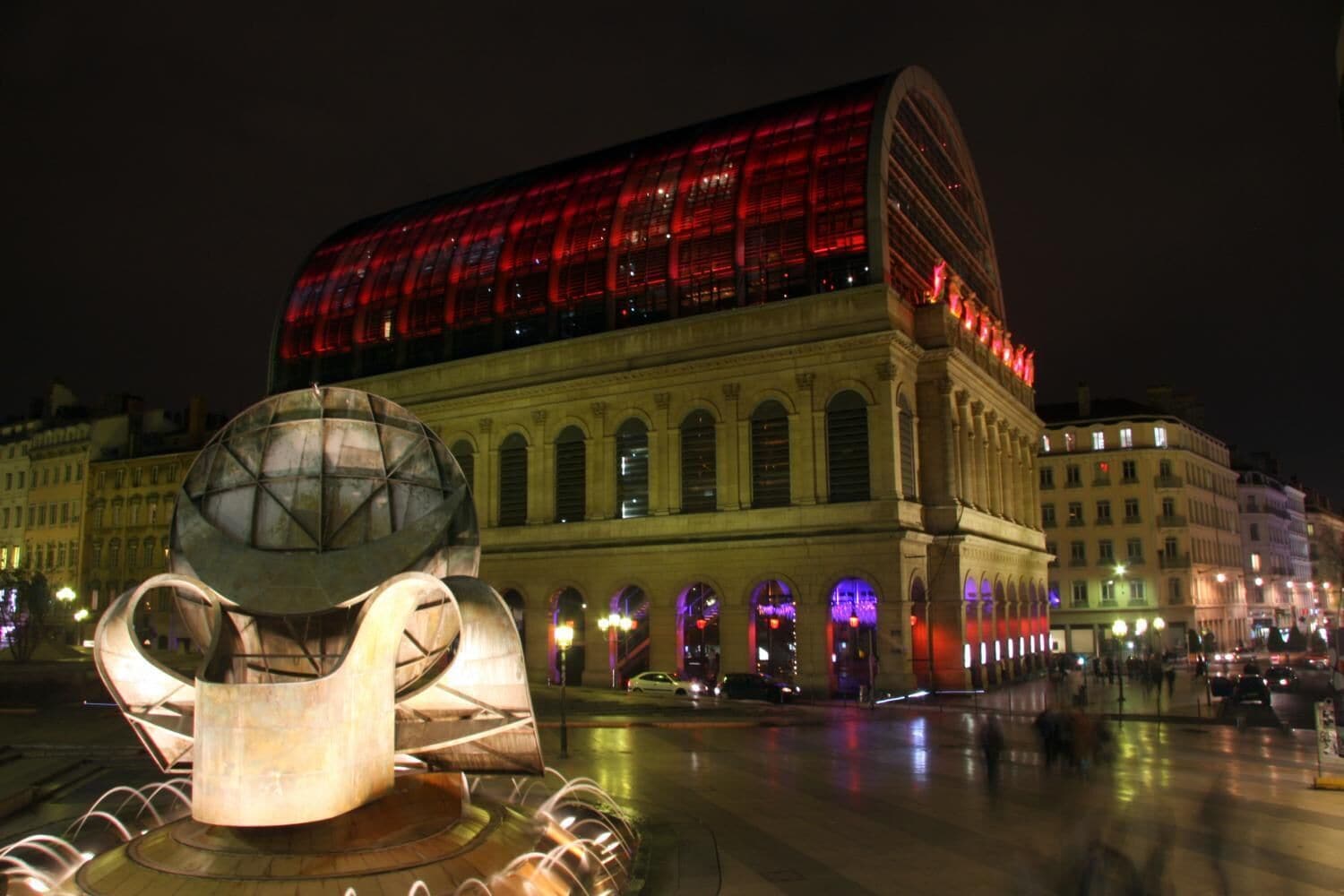 A historic building with a large glass facade and a modern sculpture in the foreground.