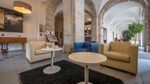 Un vestíbulo amplio con techos altos, arcos de piedra y zonas de estar modernas.