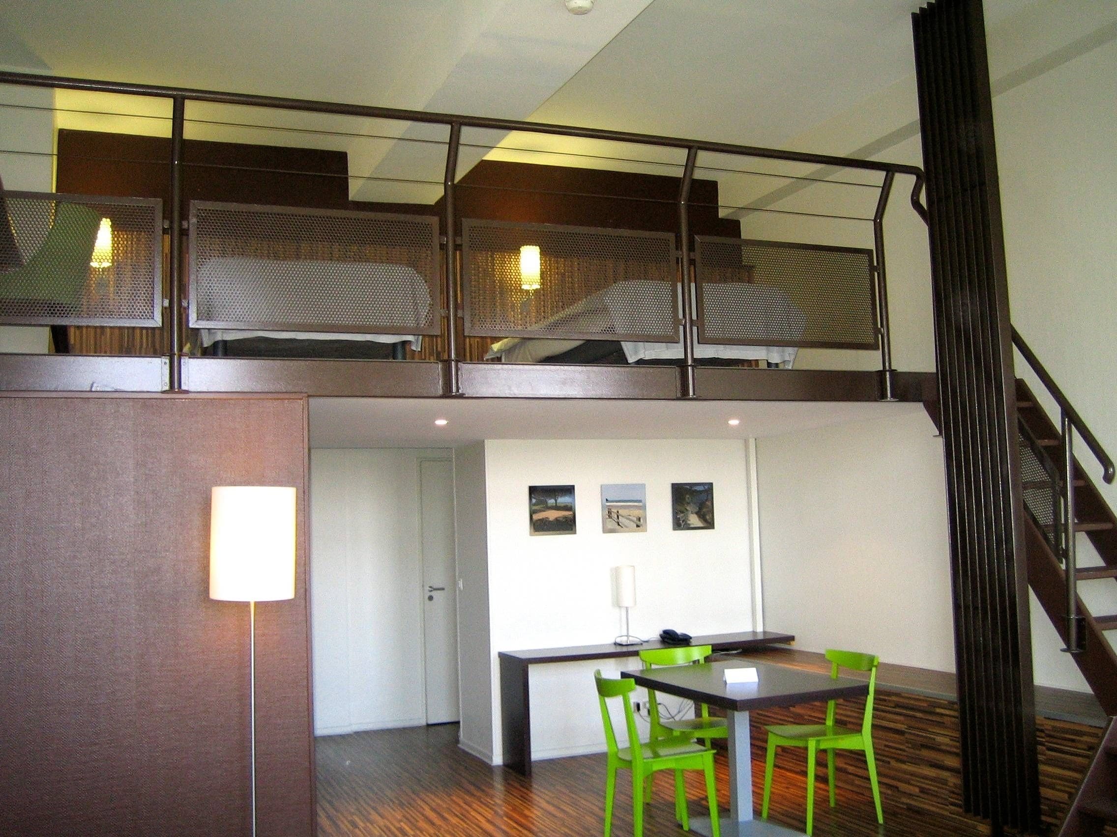 Un appartement moderne de style « loft », comprenant un espace repas, un escalier et une mezzanine avec une rambarde.