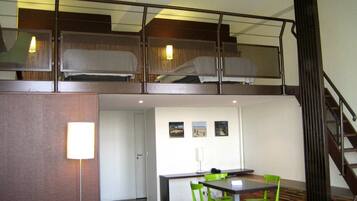 Un appartement moderne de style « loft », comprenant un espace repas, un escalier et une mezzanine avec une rambarde.