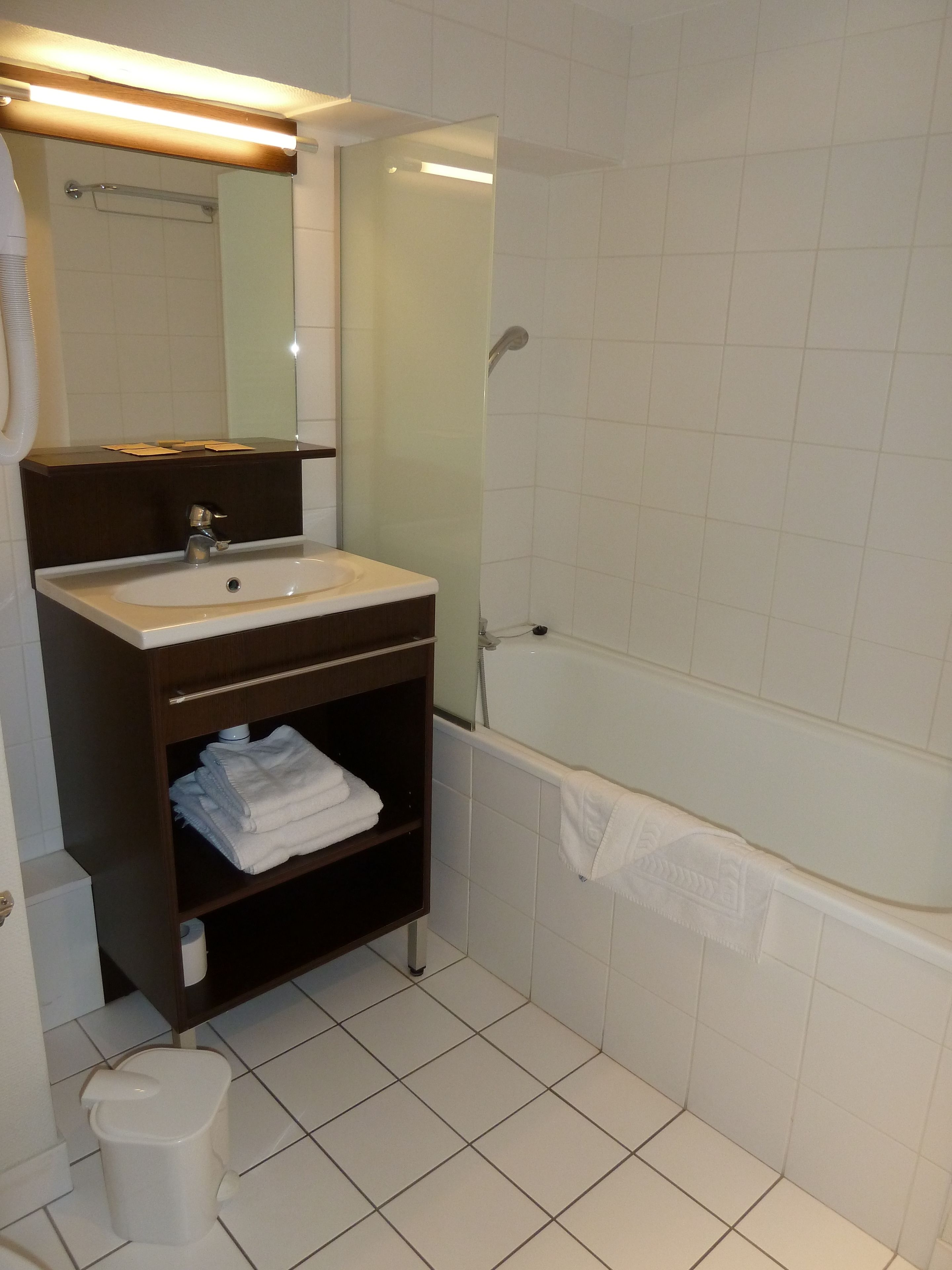 Une salle de bain équipée d’un lavabo, d’un miroir, d’un porte-serviettes et d’un espace douche.