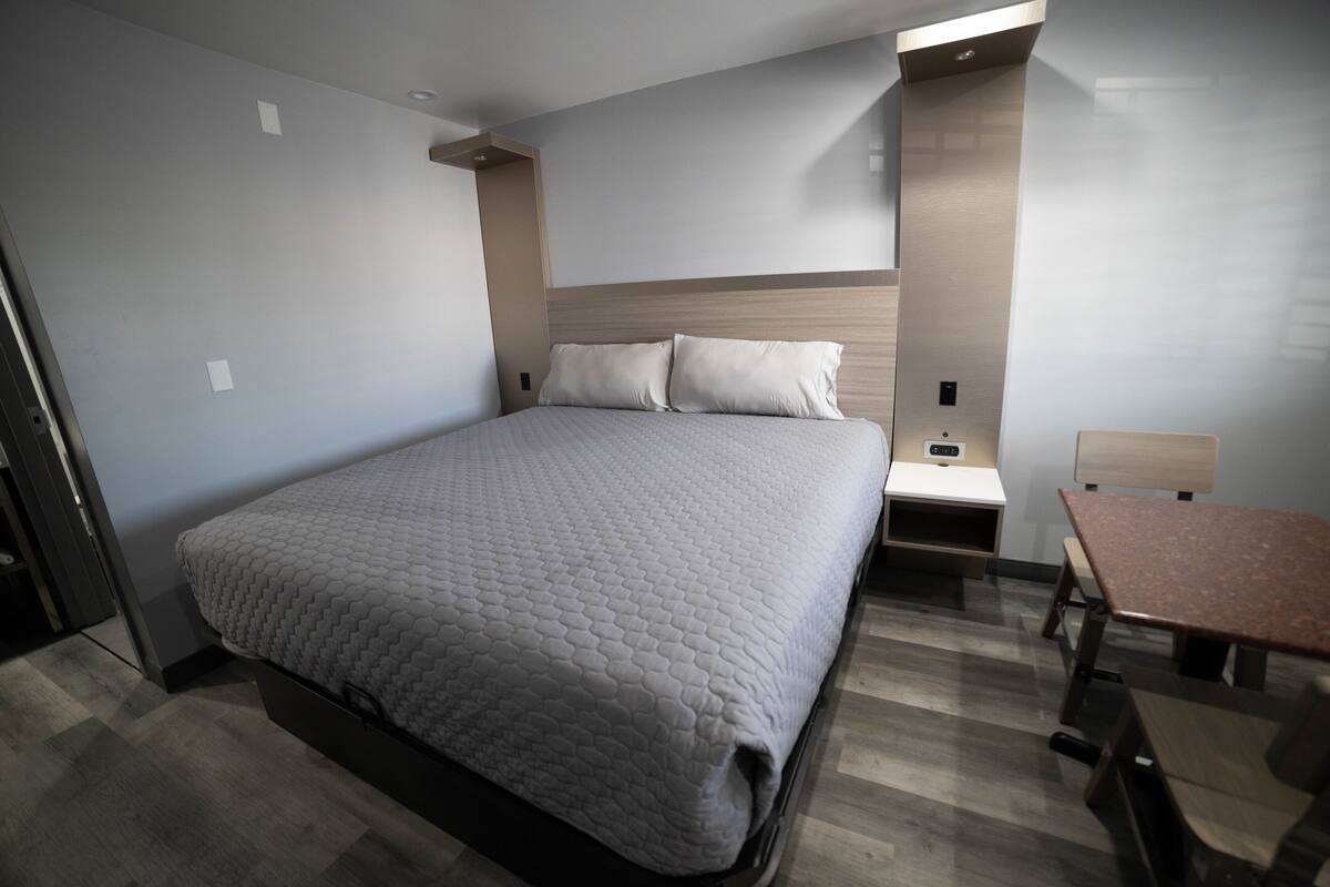 A modern hotel room with a large bed, a desk, and a chair.