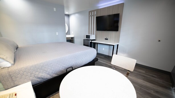Une chambre d’hôtel moderne, dotée d’un grand lit, d’un petit bureau, d’un téléviseur à écran plat et d’une table ronde.