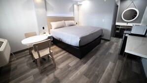 Une chambre à coucher moderne avec un lit, une table de chevet et un petit miroir rond.