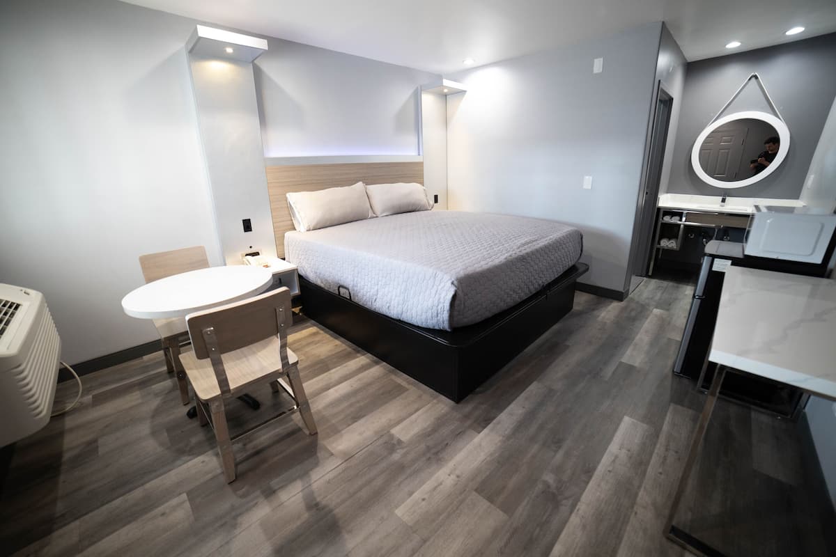 A modern bedroom with a bed, bedside table, and a small round mirror.