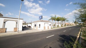 Une vue de rue avec une enseigne de motel, un ciel dégagé et une route bordée de palmiers.