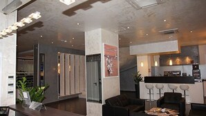 A modern hotel lobby with a reception desk, seating area, and a kitchenette. - ABC Hotel (Algiers)