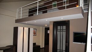 A modern interior with a high ceiling, a mezzanine level, a dark wooden door, and a flat-screen TV mounted on the wall. - ABC Hotel (Algiers)