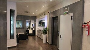 A modern hotel lobby with a reception desk, a white door, and a fire extinguisher on the wall. - ABC Hotel (Algiers)