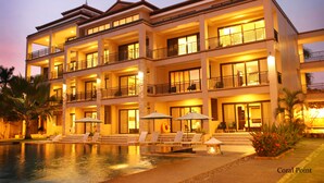 A multi-story hotel with a swimming pool, balconies, and outdoor seating. - Coralpoint Gardens (Lapu-Lapu)