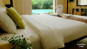 A 1-bed room with a bed, pillows, a view of a pool, and a TV. - Coralpoint Gardens (Lapu-Lapu)