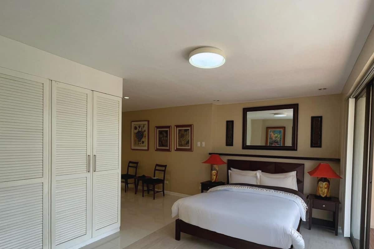 A bedroom with a bed, a wardrobe, a mirror, and a chair.