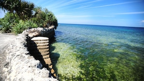 A clear view of a coastal area with a rocky ledge and calm sea. - Coralpoint Gardens (Lapu-Lapu)