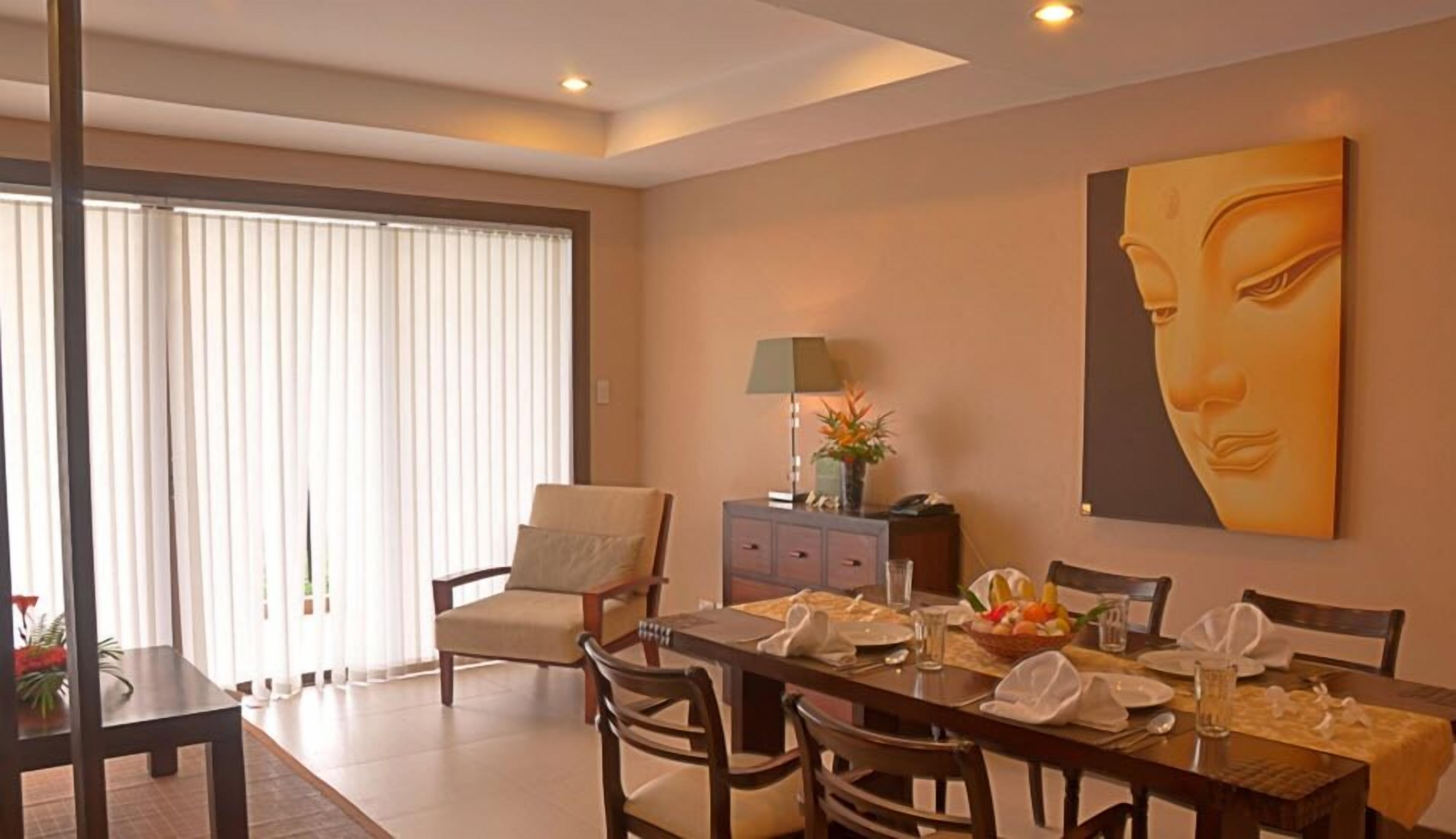 A dining area with a table set for four, a sofa, and a painting on the wall.
