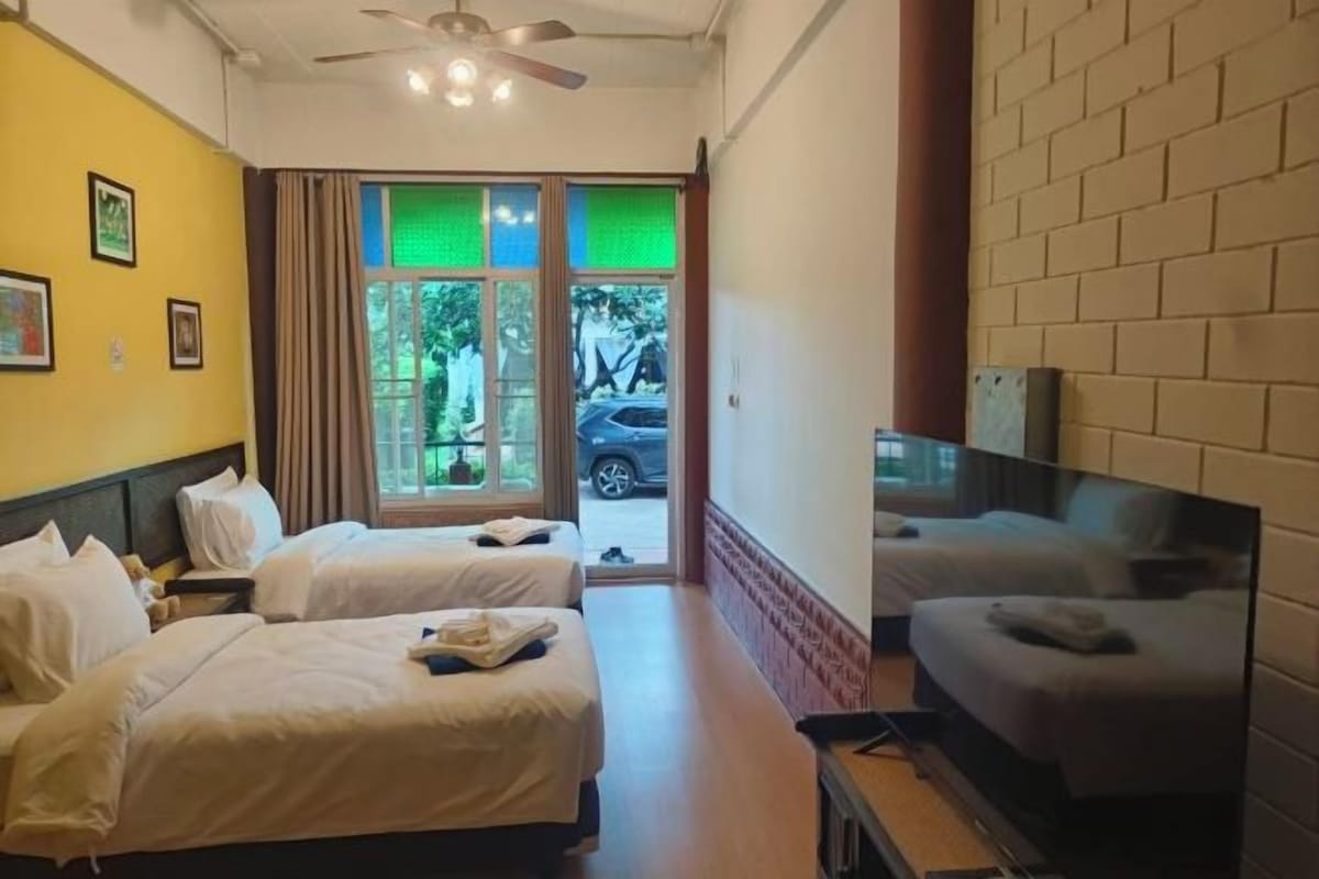 Une chambre d’hôtel avec deux lits, un canapé, une télévision et une vue sur l’extérieur.