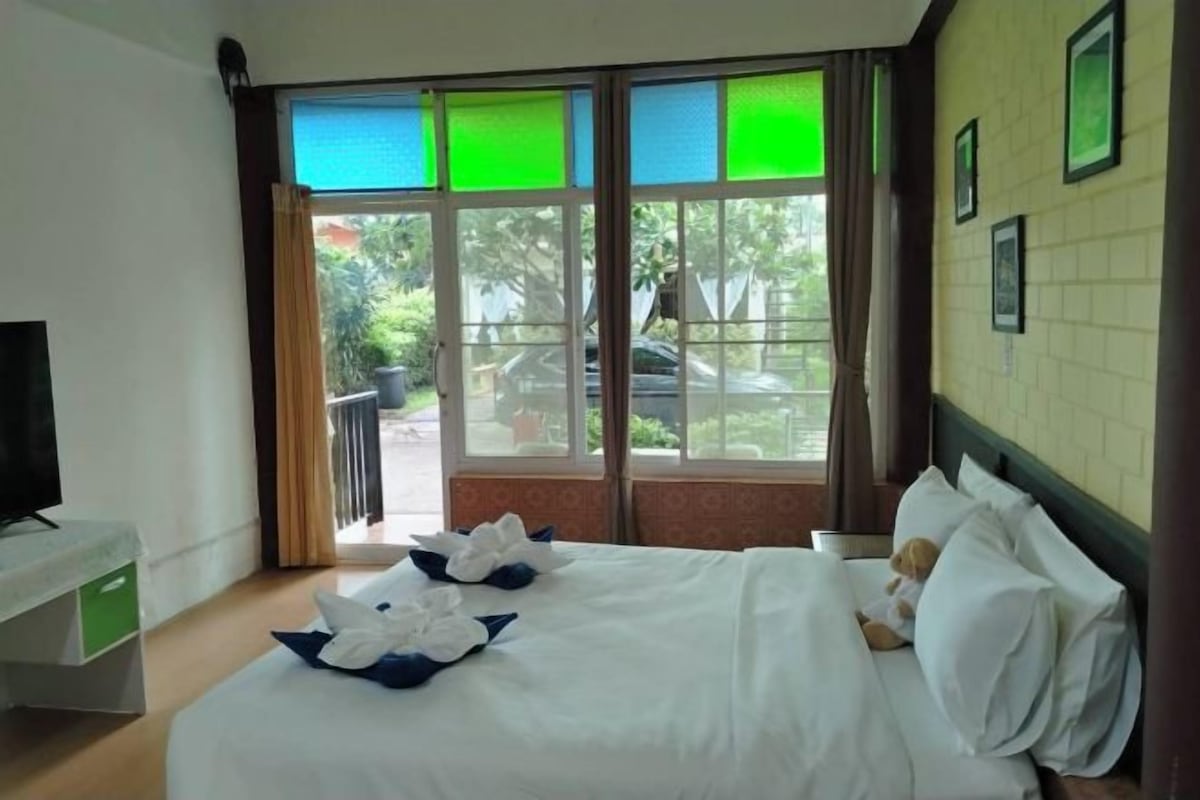 Une chambre d’hôtel avec un lit, une télévision et une fenêtre donnant sur l’extérieur.