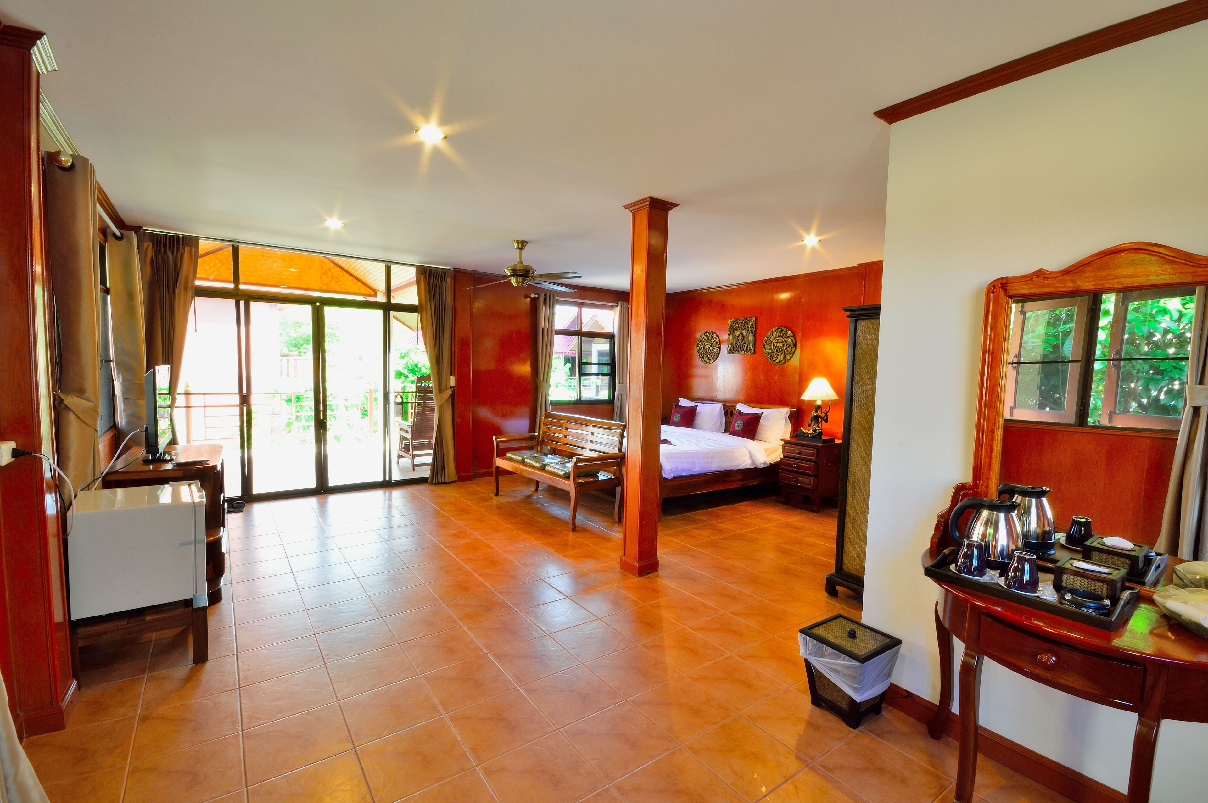 A spacious room with a bed, a desk, a chair, and a coffee station.