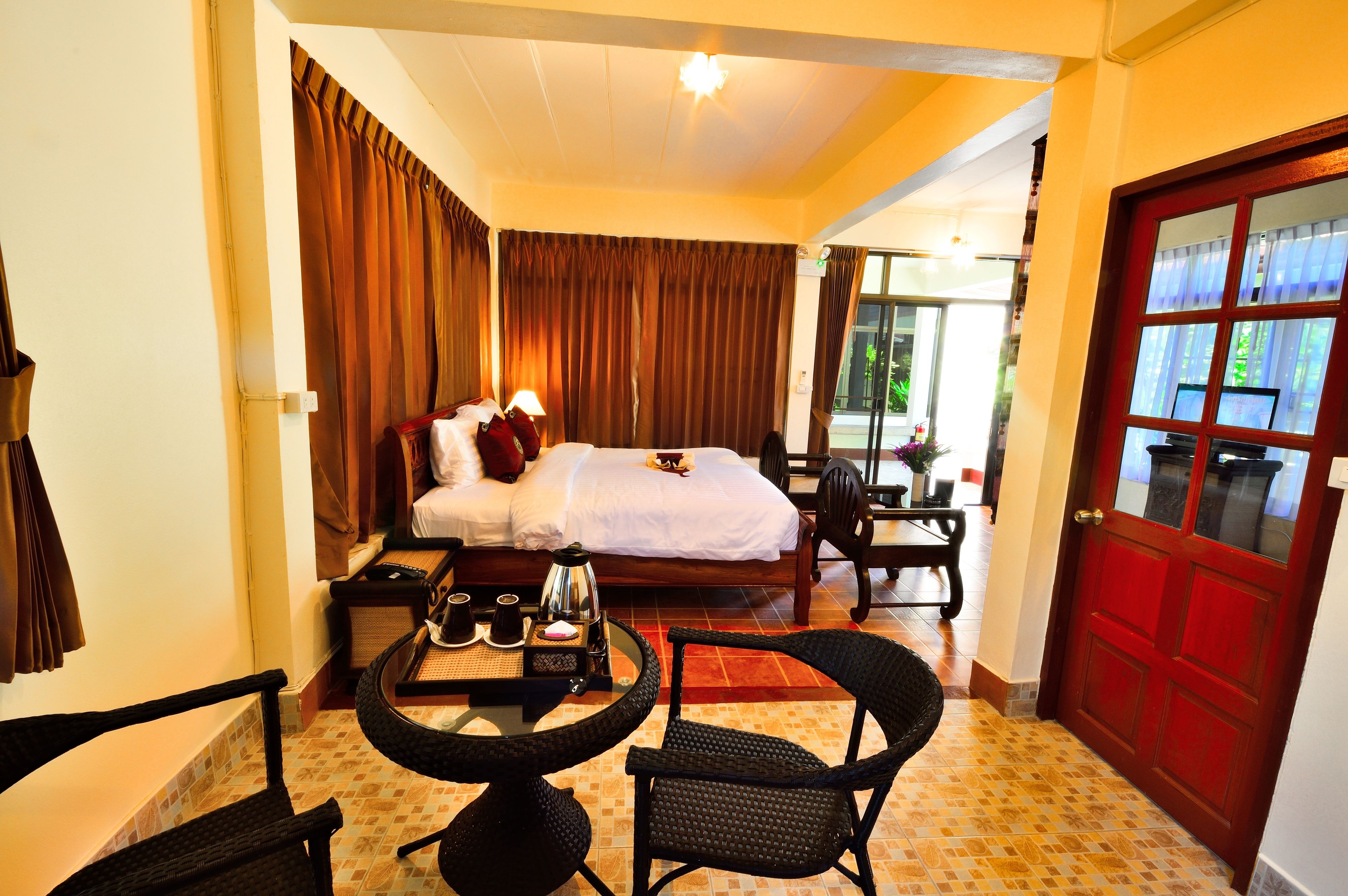 A hotel room with a bed, a small table with a tray of items, a chair, and a red door.