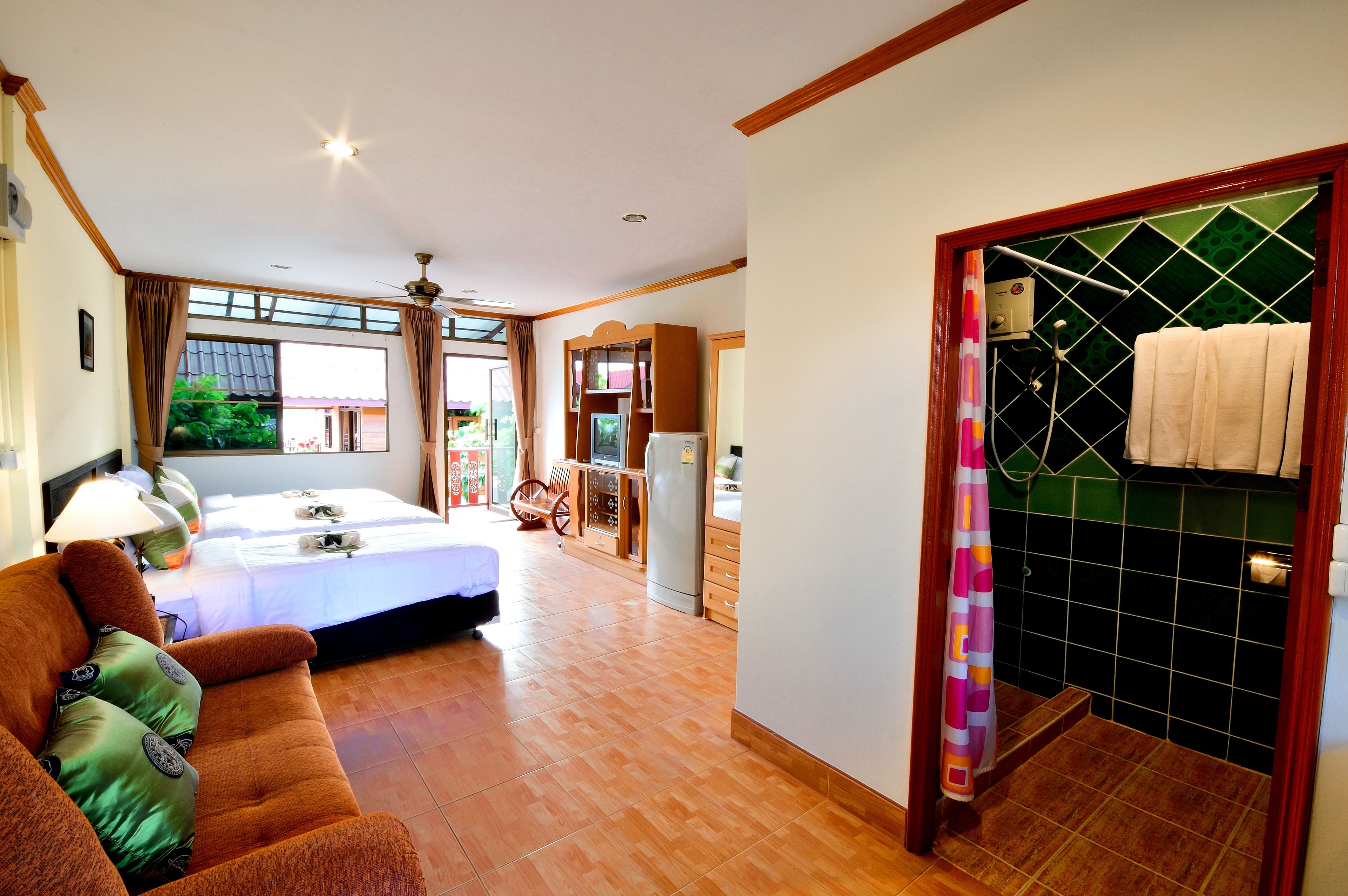 A hotel room with a bed, a sofa, a dining area, and a bathroom.