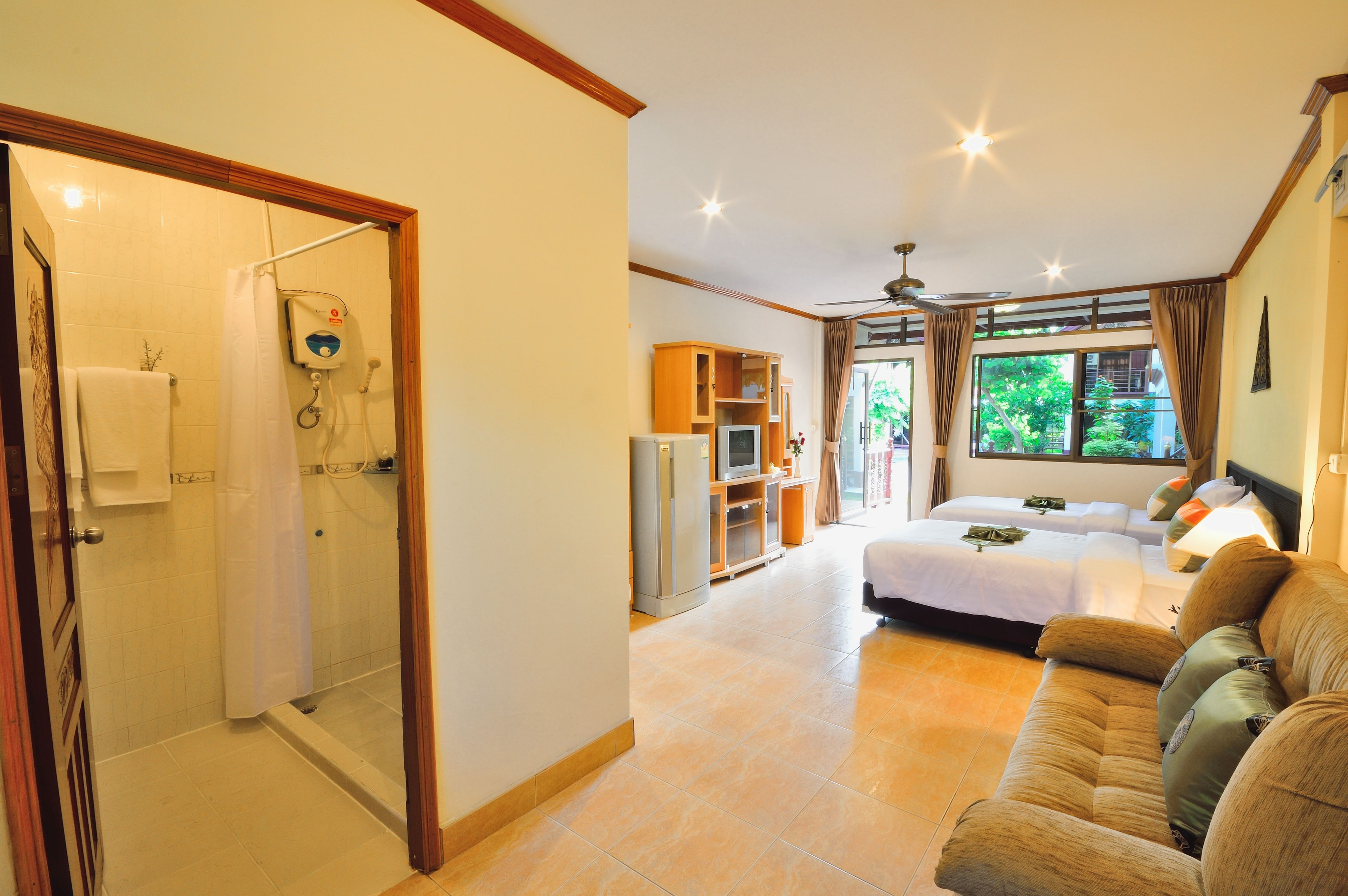 A hotel room with a shower, a bed, a sofa, and a TV.
