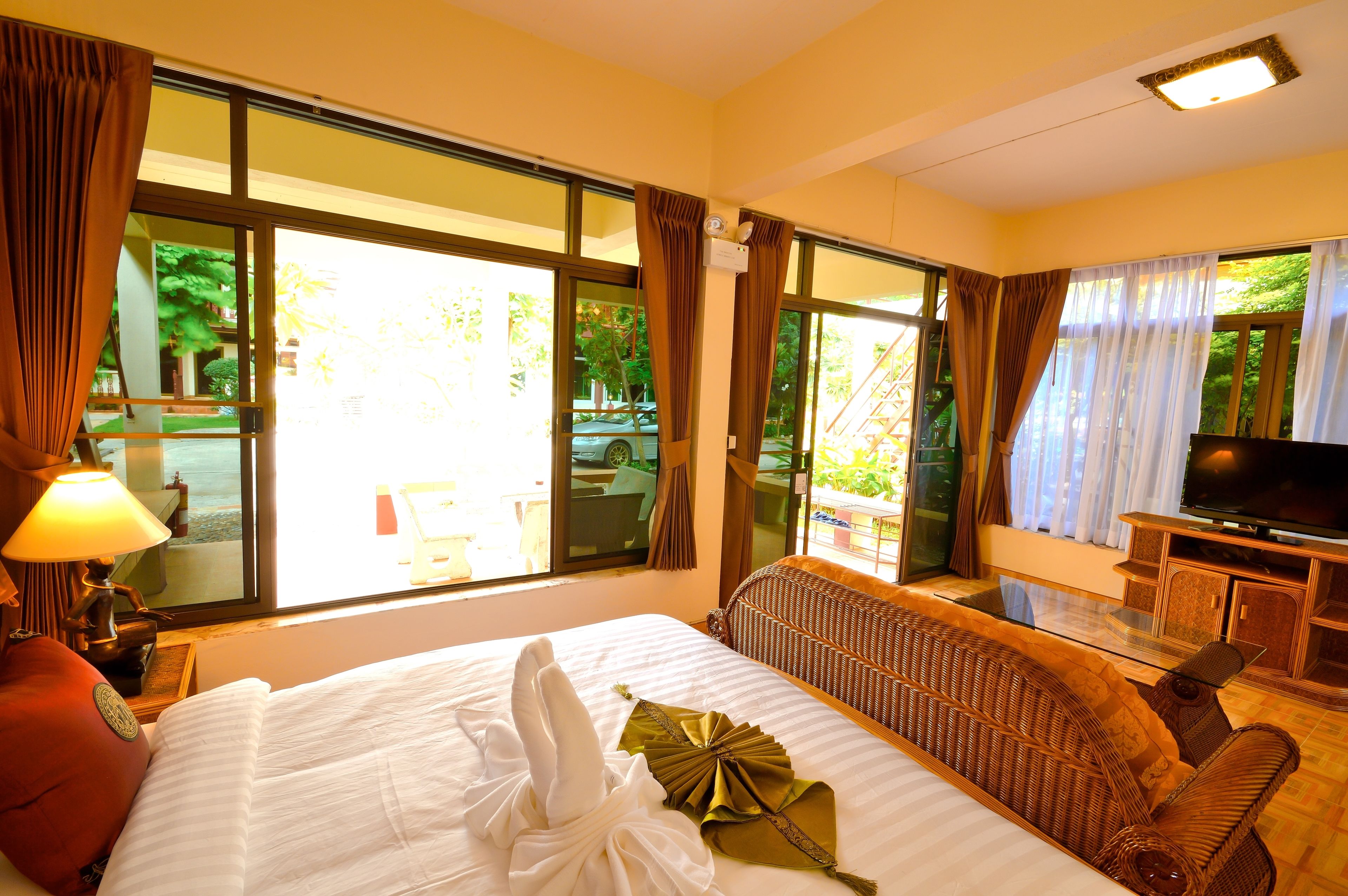A hotel room with a large bed, a TV, and a view of the outdoors.