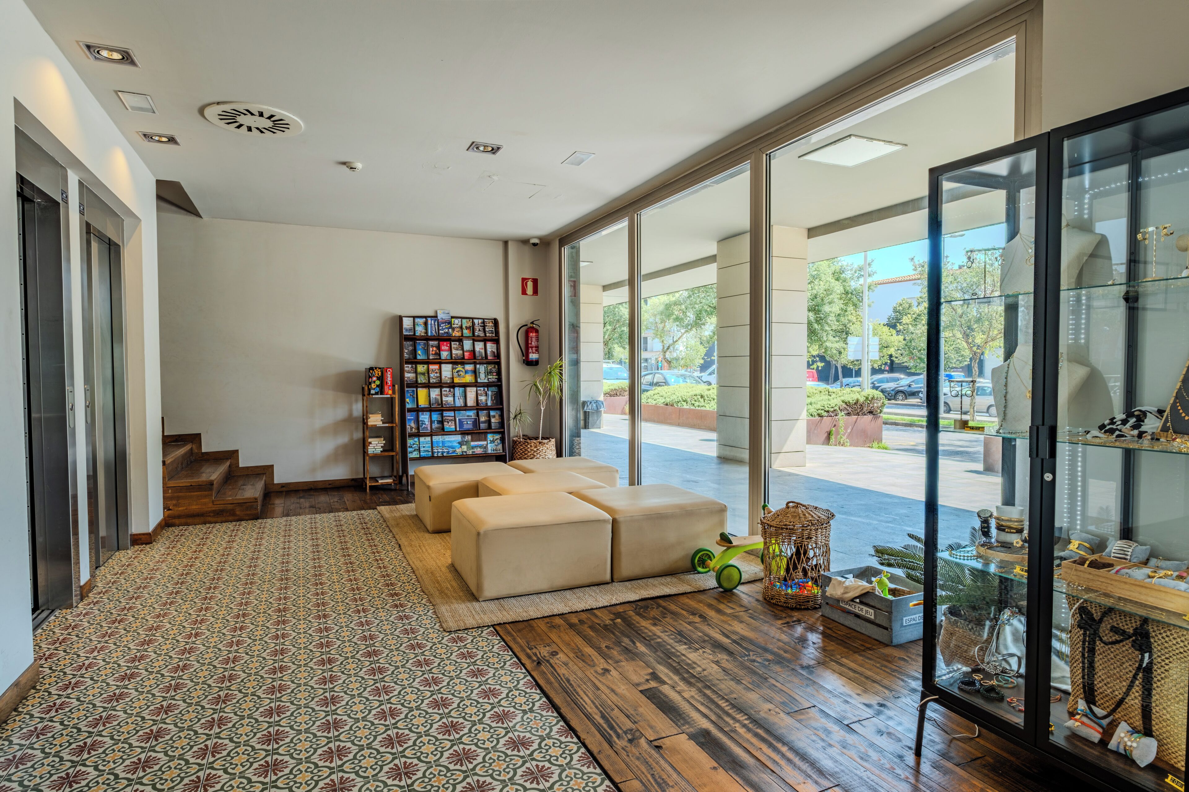 A modern interior with a staircase, a bookshelf, a seating area, and a glass display case.