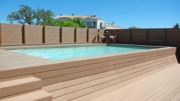 Relax by the pool surrounded by a wooden deck and comfortable seating.