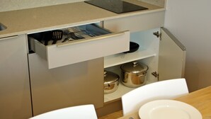 Cocina compacta con un cajón de utensilios, una encimera con una tableta y un comedor con mesa lista para dos.