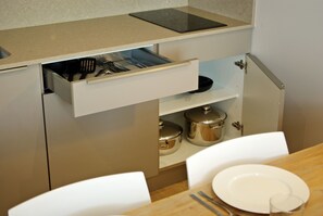 Cocina compacta con un cajón de utensilios, una encimera con una tableta y un comedor con mesa lista para dos.