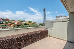 Una terraza en la azotea con barandilla de metal, vista panorámica de la ciudad y cielo despejado.