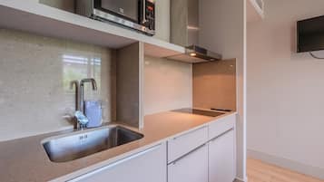 Una cocina moderna con un lavamanos de acero inoxidable, un microondas y un horno empotrado.