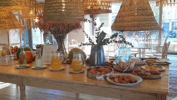 A breakfast buffet with wicker hanging lights, a variety of pastries, and a tiled floor.