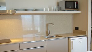 Una cocina compacta con microondas, fregadero y comedor con mesa dispuesta para dos.