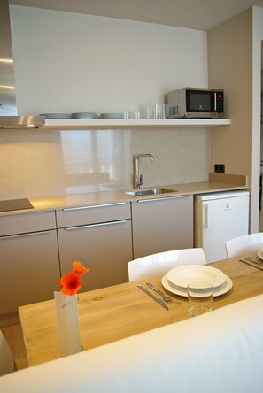 Una cocina compacta con microondas, fregadero y comedor con mesa dispuesta para dos.