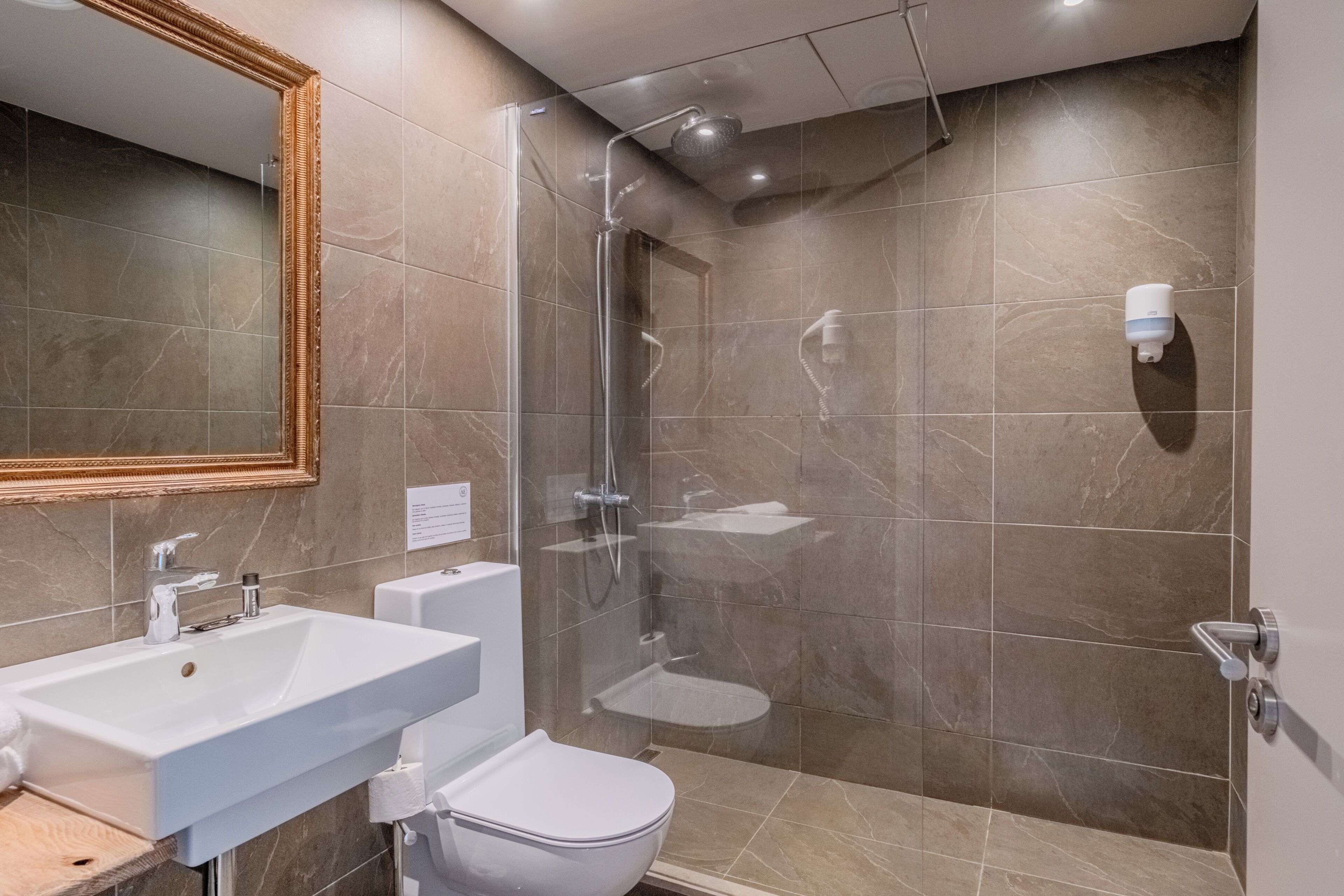 Un baño moderno con ducha envuelta en vidrio, un lavabo blanco y un inodoro.